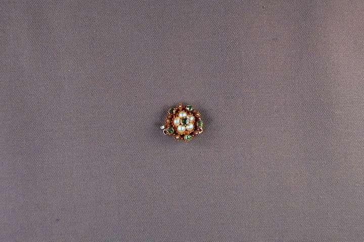 Antique emerald and seed pearl cluster snap mounted in filigree gold with a central emerald surrounded by five seed pearls and a border of five spaced emeralds